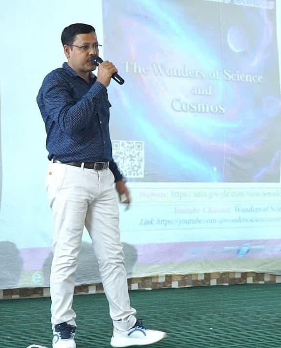 Prodyut Kanti (P. K.) Sarkar addressing a WSCosmos session, microphone in hand, in front of a projected title slide reading “The Wonders of Science and Cosmos”.