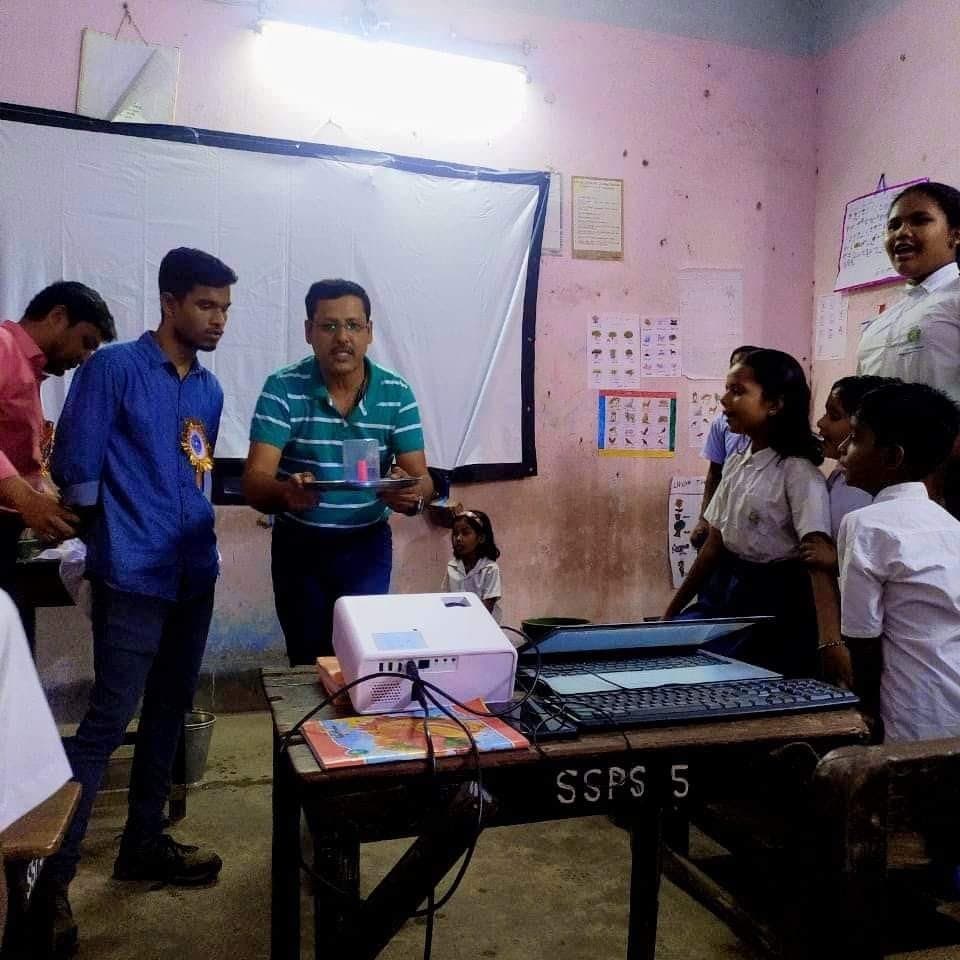 Facilitators and students around a table carrying a projector and keyboard.