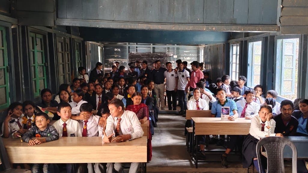 A long room filled with young students at desks, looking towards the front.