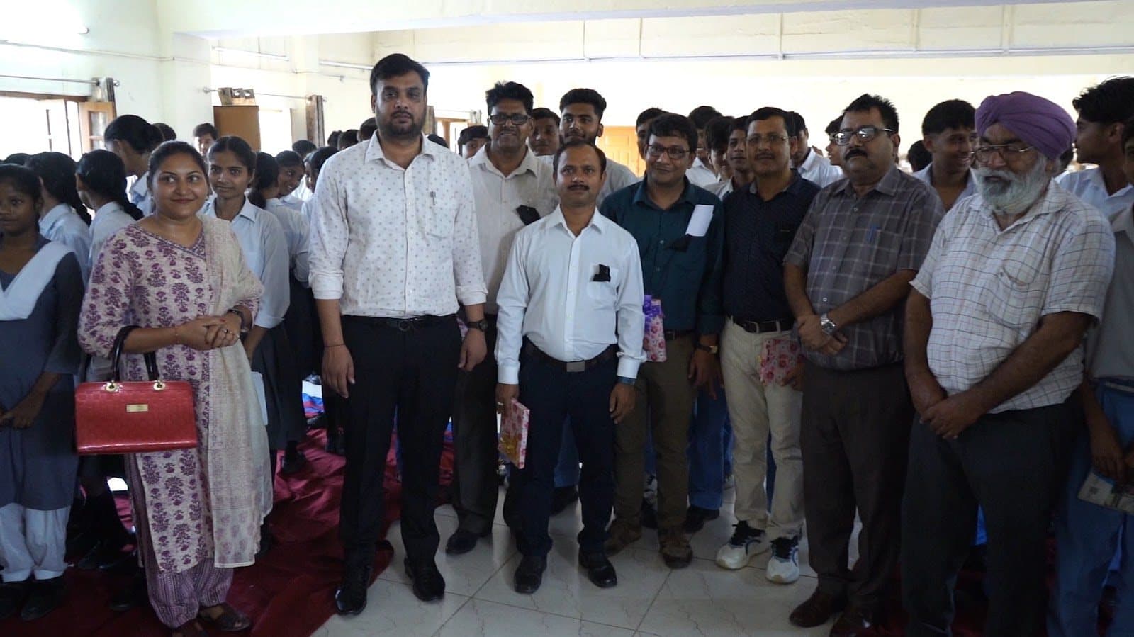 Adults and students standing together in a school hall at the end of a session.