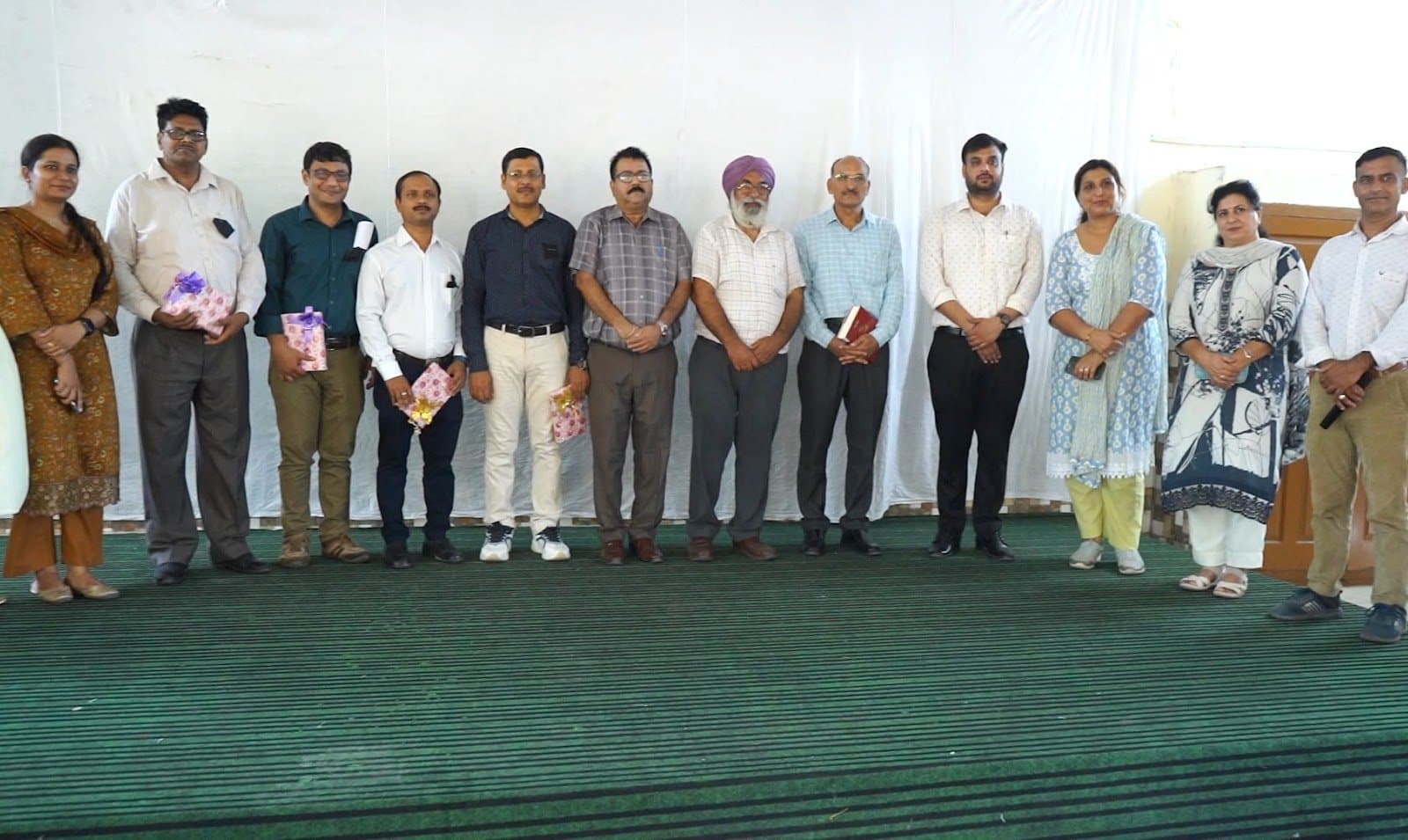 Facilitators and school staff standing in a line across a stage.
