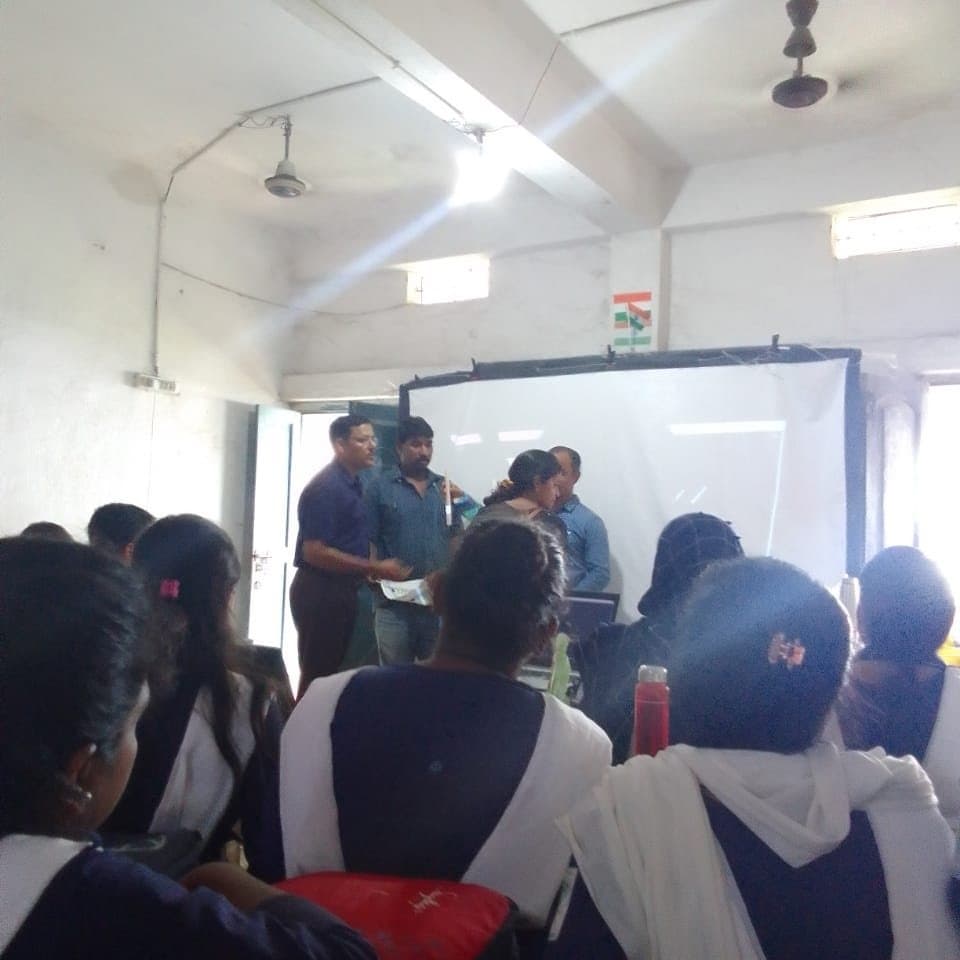 Students seen from behind, watching a demonstration at the front of a classroom.
