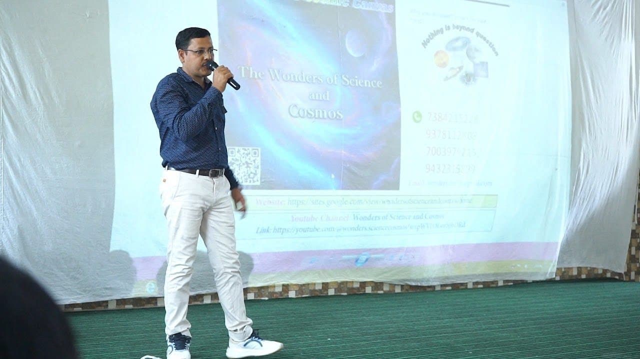 A speaker with a microphone standing before a projected WSCosmos title slide.