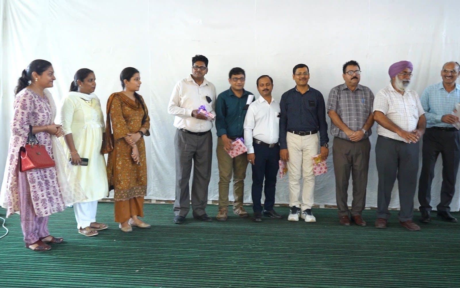 Facilitators and school staff standing in a line across a stage at the close of a session.