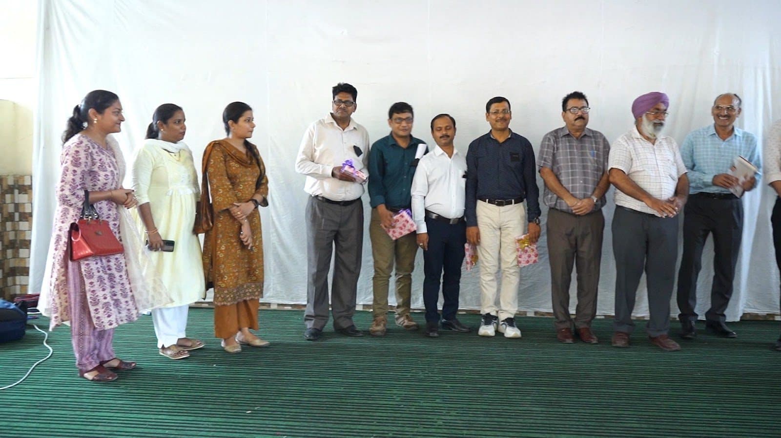 Facilitators and school staff standing together across a stage.