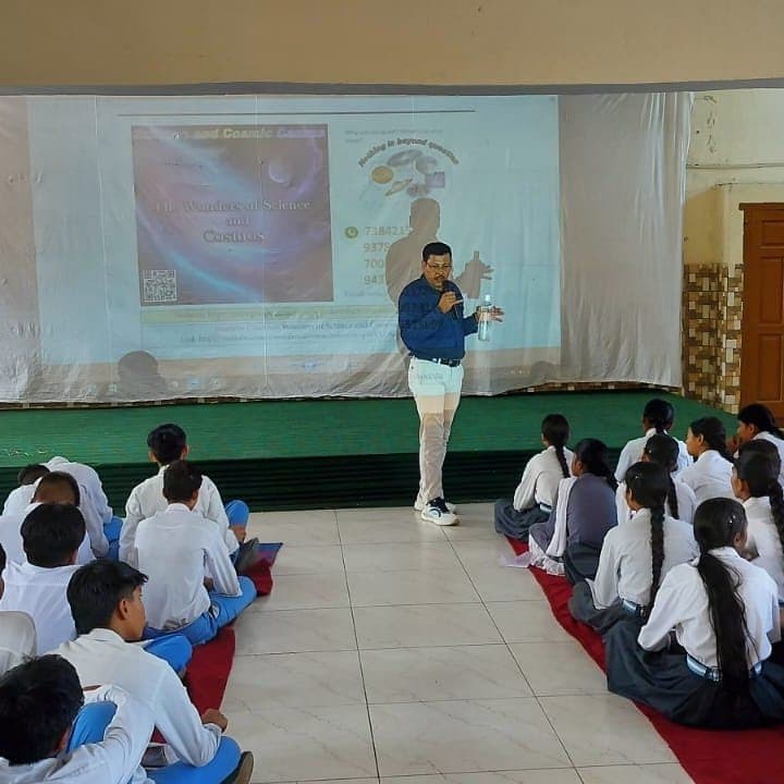 A speaker standing before a projected WSCosmos slide with students seated on the floor.