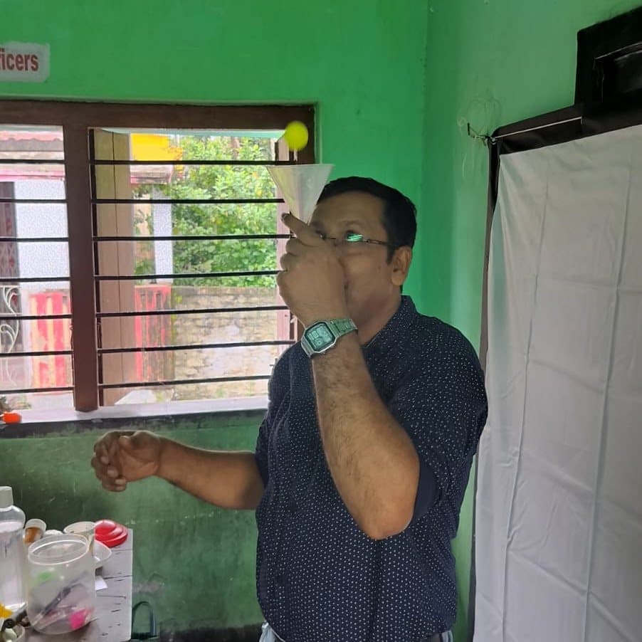 A facilitator holding a funnel to his mouth during a demonstration beside a window.